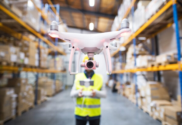 Man or a worker with drone standing in a warehouse.