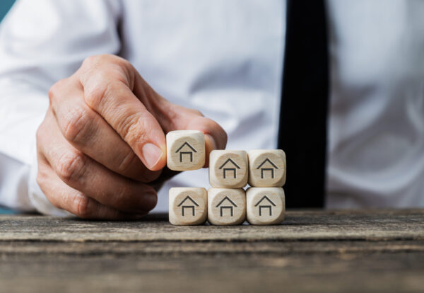 Front view of real estate agent stacking wooden dices with house symbols on them in a conceptual image.