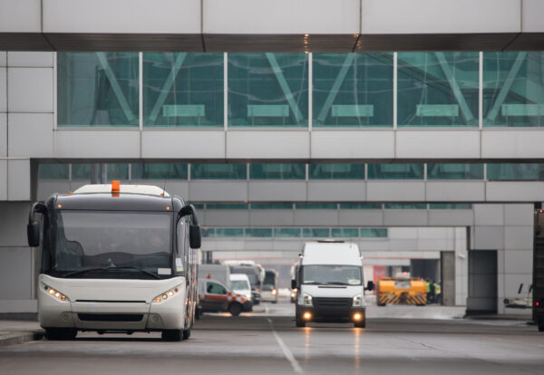 Airfield bus while driving through the airport, front view/Shuttle bus for transportation of passengers at airport terminal/Aviation services, transportation concept/