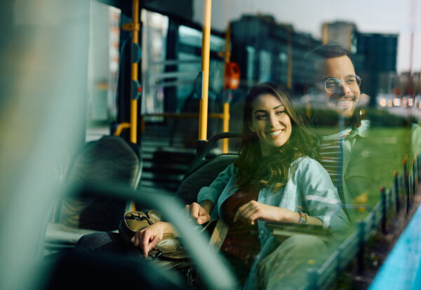 Young happy couple looking through the window while riding in a bus. Copy space.